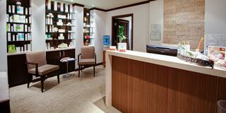 A modern reception area featuring a sleek counter, comfortable seating, and shelves stocked with skincare products, creating a welcoming atmosphere.
