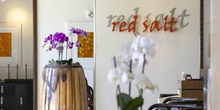 A chic restaurant entrance featuring the name "red salt" in modern lettering, complemented by elegant orchids in a wooden planter.
