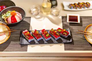 A beautifully arranged sushi platter featuring vibrant colors, garnished with toppings, accompanied by sake and other sushi dishes.