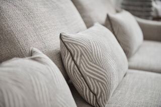 Cozy, textured sofa with several striped cushions, creating an inviting and stylish living space. Neutral tones enhance warmth and comfort.