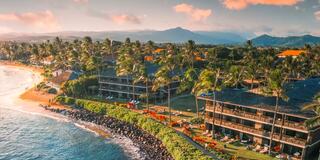 Coastal resort with palm trees, beach, and colorful villas under a serene sky, capturing a tranquil tropical paradise.