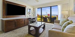 A stylish living area featuring a comfortable sofa, sleek furniture, a large TV, and a stunning view of a garden and ocean through sliding doors.