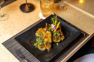 A beautifully plated dish of flavorful, herb-crusted lamb chops garnished with edible flowers and herbs, set on an elegant table.