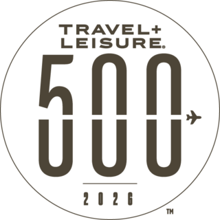 A circular logo featuring "TRAVEL+LEISURE," the number "500," and "2026," with an airplane graphic incorporated into the design.