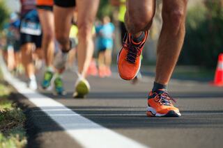 Runners push forward along a road, showcasing vibrant athletic shoes and a sense of determination in a competitive atmosphere.