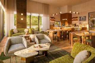 A stylish café interior featuring cozy seating, wooden accents, and large windows that invite natural light, creating a warm atmosphere.
