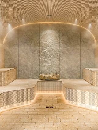 Serene spa setting with stone walls, soft lighting, and minimalist design, creating a tranquil atmosphere for relaxation.