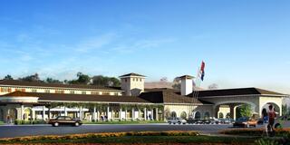 A grand, multi-story building featuring a Mediterranean-inspired design, with landscaped gardens and vehicles parked out front.