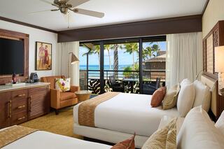 A bright, tropical hotel room featuring two beds, a balcony with ocean views, and stylish decor, offering a relaxing getaway atmosphere.